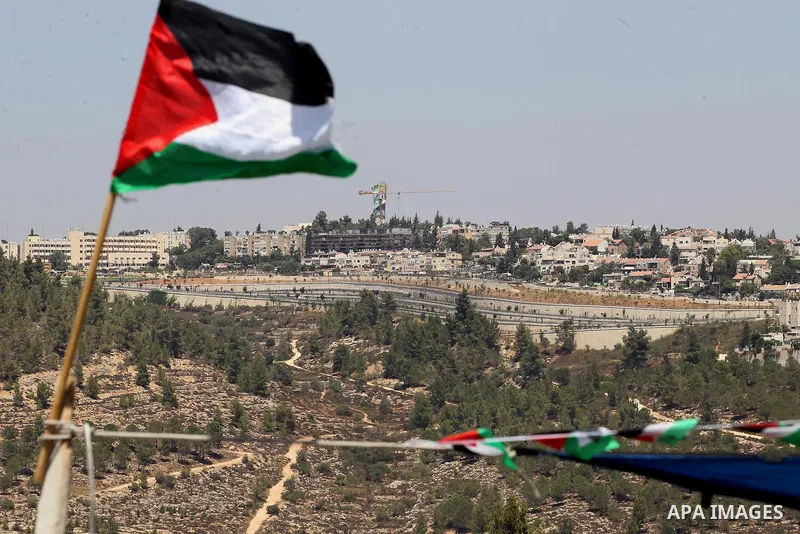 A Palestinian flag is seen in from to the Jewish settlement of Gilo, in the West Bank village of Walajeh near Bethlehem August 18, 2017. Photo by Wisam Hashlamoun