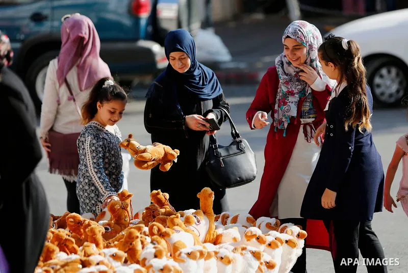 Palestinians buy toys of sheep at a market ahead of the Eid al-Adha festival in the West Bank city of Hebron, on August 21, 2017. Photo by Wisam Hashlamoun