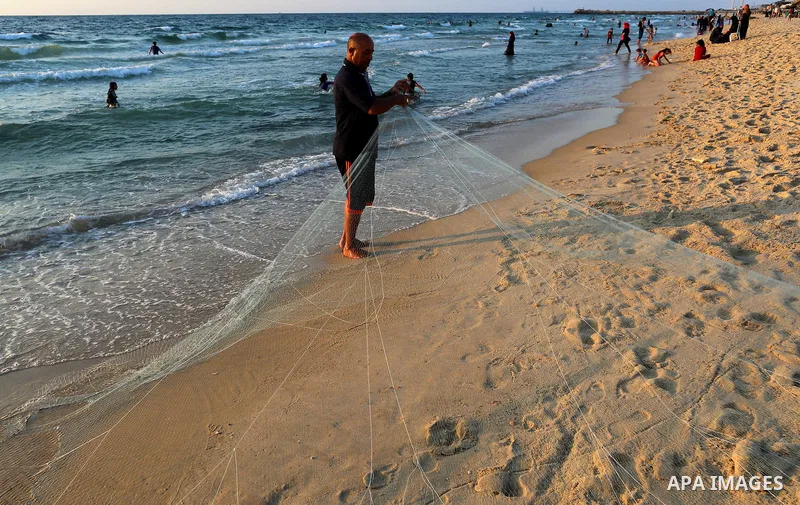 Palestinian fisherman Jihad al-Soltan prepares his fishing net on a beach in the northern Gaza Strip August 21, 2017. Photo by Yasser Qudih