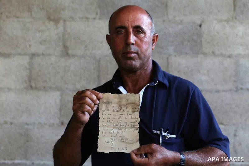 Palestinian fisherman Jihad al-Soltan displays a message that was written by Bethany Wright and her boyfriend Zac Marriner, after he found it in a bottle off a Gaza beach, in Gaza August 21, 2017. Photo by Yasser Qudih