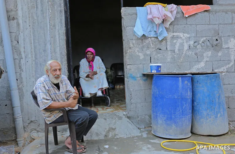 Palestinians sit outside their house at el-shate refugee camp in Gaza, on August 22, 2017. Photo by Ashraf Amra
