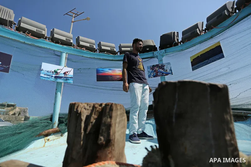 Palestinians attend a photo gallery on fishing boat, in Gaza seaport, on August 23, 2017. Photo by Ashraf Amra