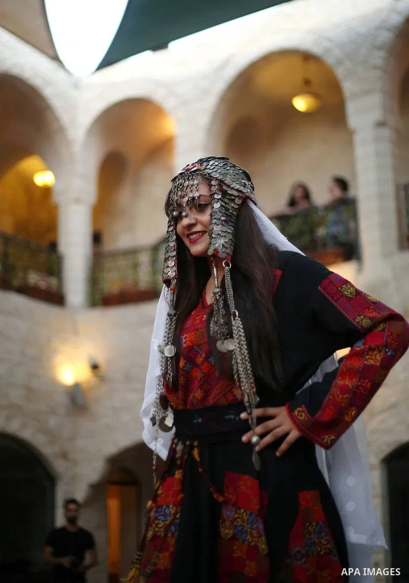 A Palestinian woman wearing traditional dress creation takes part during a fashion show marking Traditional Palestinian Dress Day, in the West Bank city of Nablus on August 22, 2017. Photo by Ayman Ameen