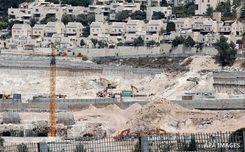 Construction workers build new houses in an Israeli settlement, in the West Bank village of Walajeh, near Bethlehem, on August 25, 2017. Photo by Wisam Hashlamoun