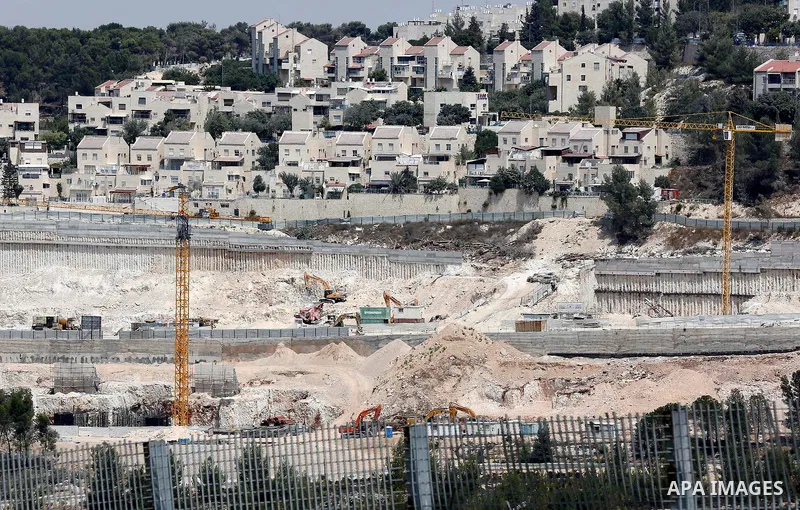 Construction workers build new houses in an Israeli settlement, in the West Bank village of Walajeh, near Bethlehem, on August 25, 2017. Photo by Wisam Hashlamoun