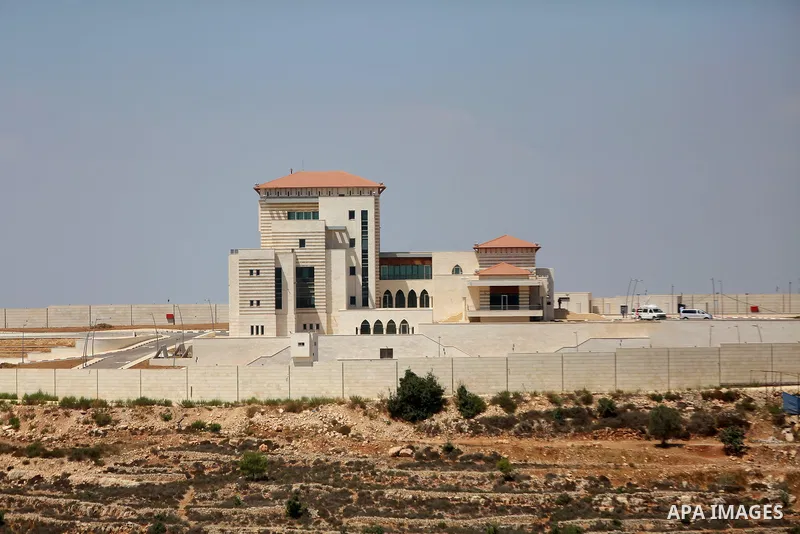 A picture taken on August 28, 2017 shows people standing outside the presidential palace near the city of Ramallah in the occupied West Bank after Palestinian officials announced a project to transform the building into...