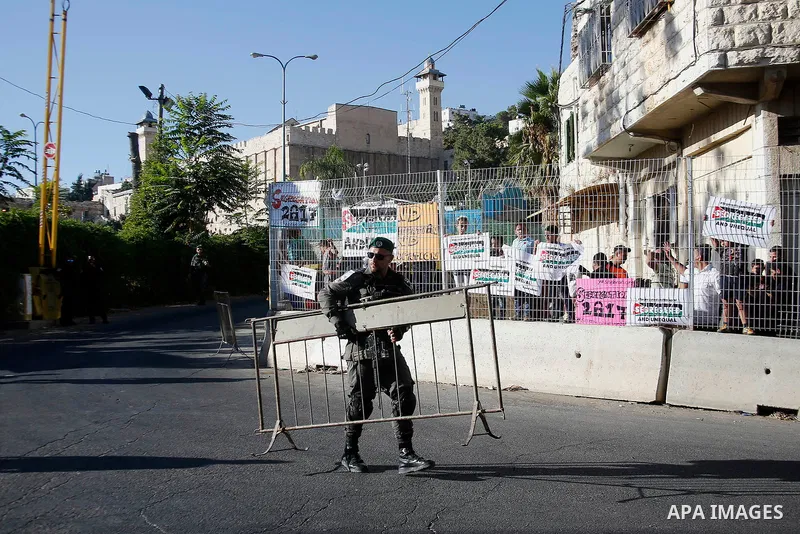 Palestinian protesters hold placards during a protest against new gates and barriers near the near the Ibrahimi mosque in the Old city of the West Bank city of Hebron on August 28, 2017. Photo by Wisam Hashlamoun
