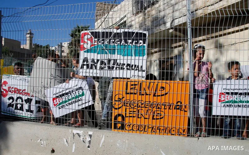 Palestinian protesters hold placards during a protest against new gates and barriers near the near the Ibrahimi mosque in the Old city of the West Bank city of Hebron on August 28, 2017. Photo by Wisam Hashlamoun