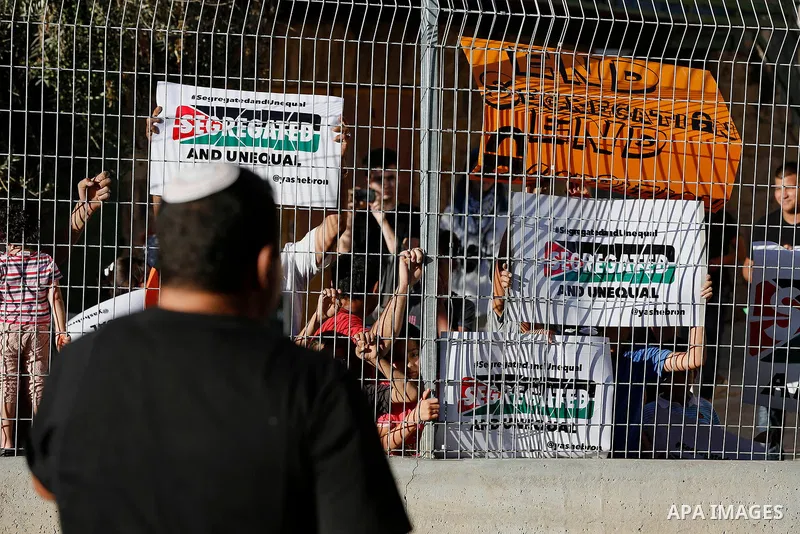 Palestinian protesters hold placards during a protest against new gates and barriers near the near the Ibrahimi mosque in the Old city of the West Bank city of Hebron on August 28, 2017. Photo by Wisam Hashlamoun