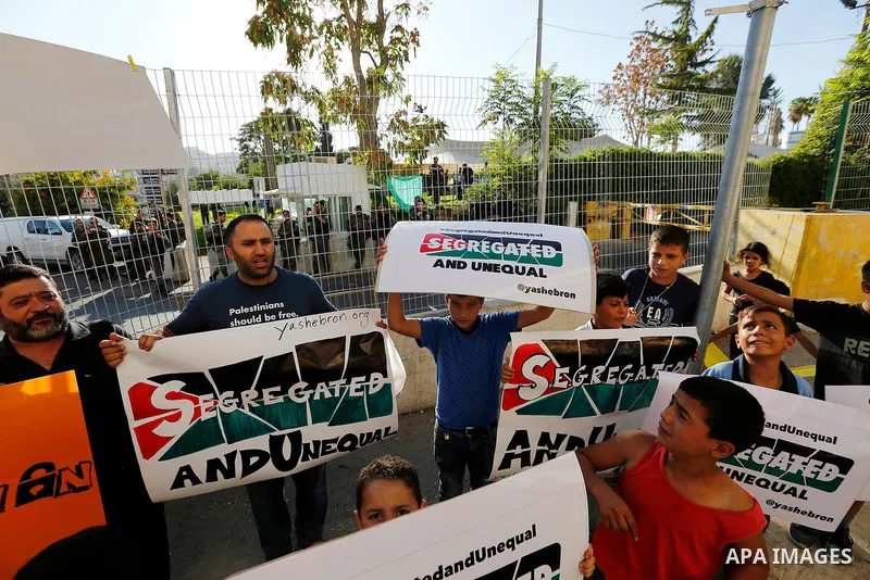Palestinian protesters hold placards during a protest against new gates and barriers near the near the Ibrahimi mosque in the Old city of the West Bank city of Hebron on August 28, 2017. Photo by Wisam Hashlamoun