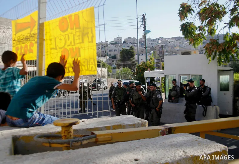 Palestinian protesters hold placards during a protest against new gates and barriers near the near the Ibrahimi mosque in the Old city of the West Bank city of Hebron on August 28, 2017. Photo by Wisam Hashlamoun