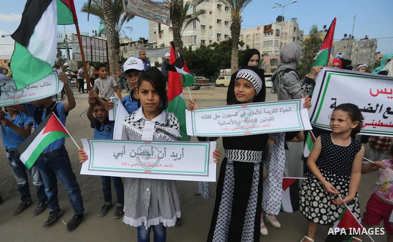 Palestinians hold placards upon arrival of United Nations Secretary General Antonio Guterres in Beit Lahia in the northern Gaza Strip on August 30, 2017. Photo by Mohammed Asad