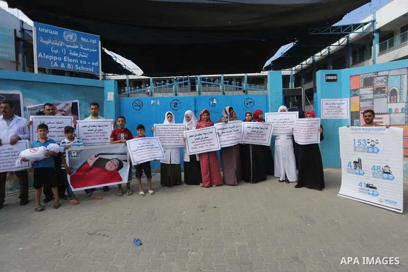 Palestinians hold placards upon arrival of United Nations Secretary General Antonio Guterres in Beit Lahia in the northern Gaza Strip on August 30, 2017. Photo by Mohammed Asad