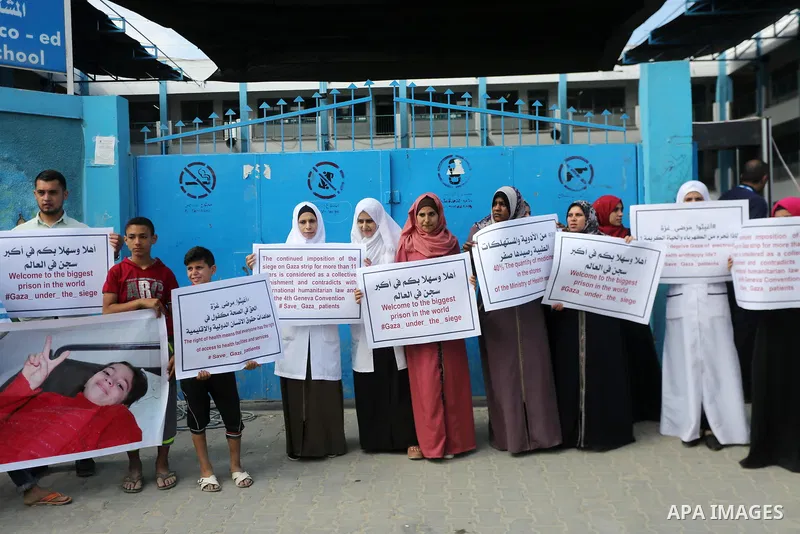 Palestinians hold placards upon arrival of United Nations Secretary General Antonio Guterres in Beit Lahia in the northern Gaza Strip on August 30, 2017. Photo by Mohammed Asad