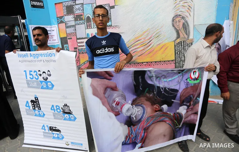 Palestinians hold placards upon arrival of United Nations Secretary General Antonio Guterres in Beit Lahia in the northern Gaza Strip on August 30, 2017. Photo by Mohammed Asad