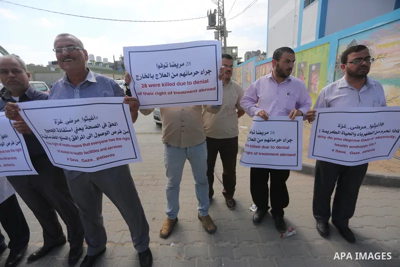 Palestinians hold placards upon arrival of United Nations Secretary General Antonio Guterres in Beit Lahia in the northern Gaza Strip on August 30, 2017. Photo by Mohammed Asad