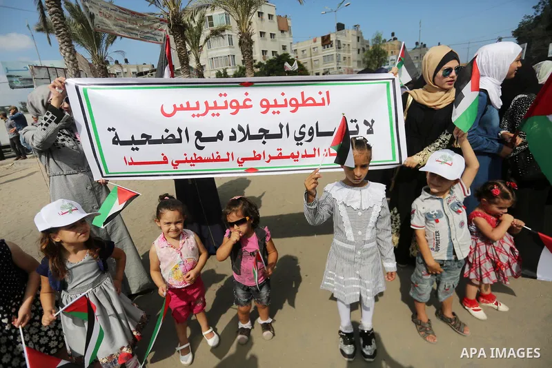 Palestinians hold placards upon arrival of United Nations Secretary General Antonio Guterres in Beit Lahia in the northern Gaza Strip on August 30, 2017. Photo by Mohammed Asad
