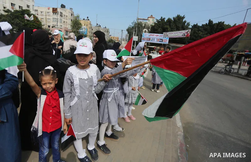 Palestinians hold placards upon arrival of United Nations Secretary General Antonio Guterres in Beit Lahia in the northern Gaza Strip on August 30, 2017. Photo by Mohammed Asad