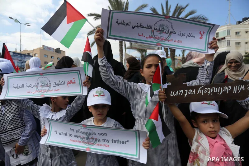Palestinians hold placards upon arrival of United Nations Secretary General Antonio Guterres in Beit Lahia in the northern Gaza Strip on August 30, 2017. Photo by Mohammed Asad