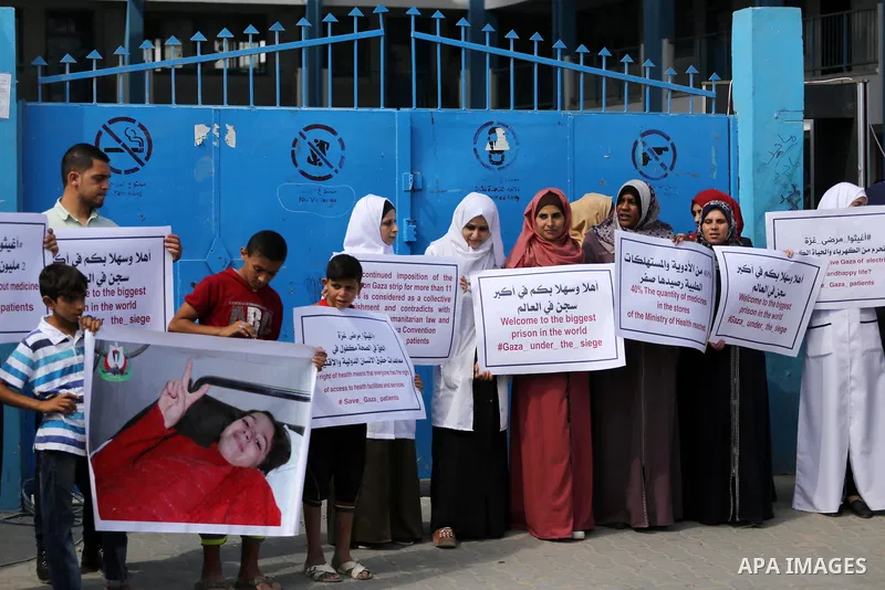Palestinians hold placards upon arrival of United Nations Secretary General Antonio Guterres in Beit Lahia in the northern Gaza Strip on August 30, 2017. Photo by Mohammed Asad