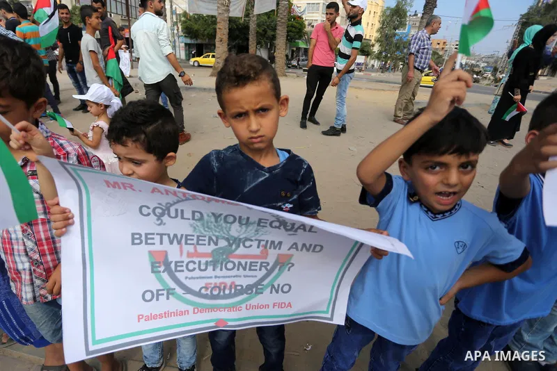 Palestinians hold placards upon arrival of United Nations Secretary General Antonio Guterres in Beit Lahia in the northern Gaza Strip on August 30, 2017. Photo by Mohammed Asad
