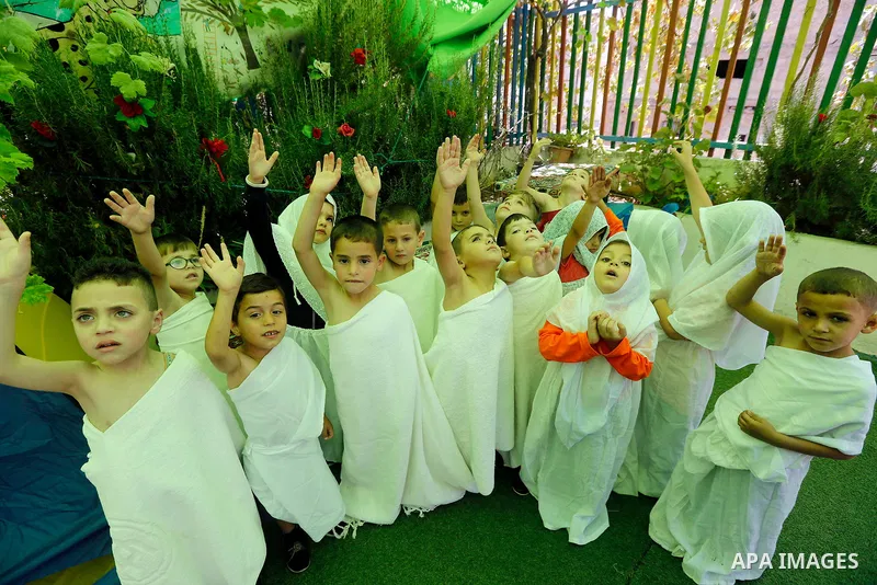 Palestinian children gather around a makeshift cube representing the holy Kaaba, in the West bank city of Hebnron, on August 30, 2017, as part of training children how to perform Hajj pilgrimage. Muslims from around the...