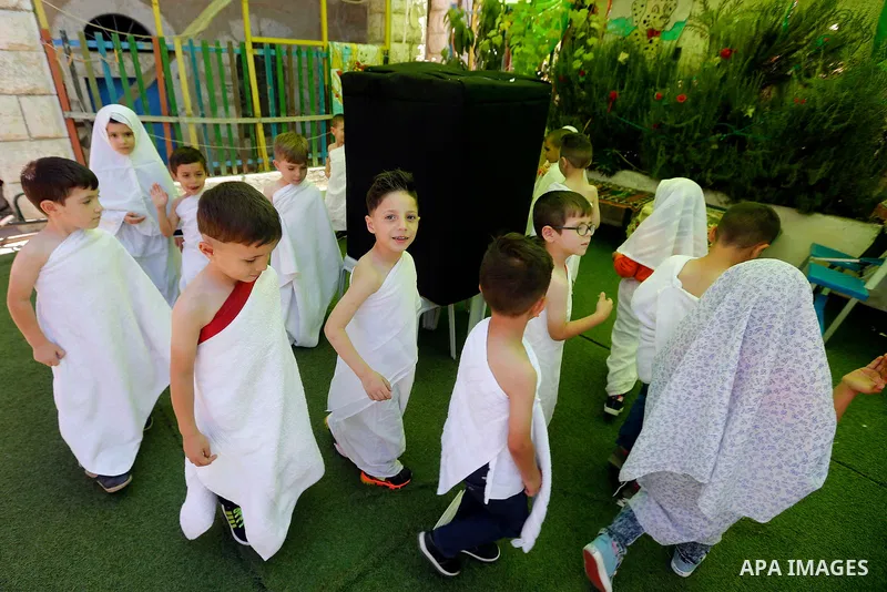 Palestinian children gather around a makeshift cube representing the holy Kaaba, in the West bank city of Hebnron, on August 30, 2017, as part of training children how to perform Hajj pilgrimage. Muslims from around the...