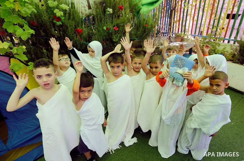Palestinian children gather around a makeshift cube representing the holy Kaaba, in the West bank city of Hebnron, on August 30, 2017, as part of training children how to perform Hajj pilgrimage. Muslims from around the...