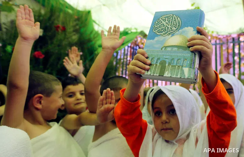 Palestinian children gather around a makeshift cube representing the holy Kaaba, in the West bank city of Hebnron, on August 30, 2017, as part of training children how to perform Hajj pilgrimage. Muslims from around the...