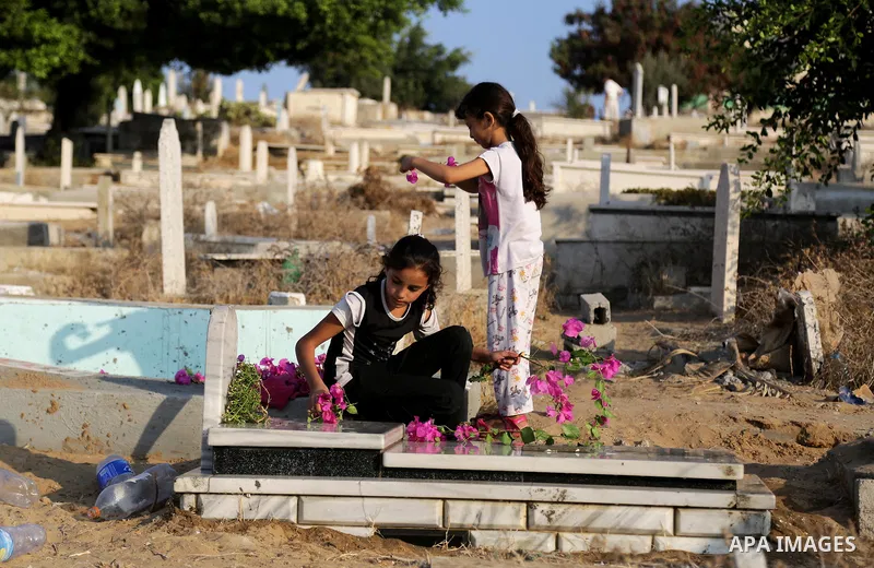 Palestinian girls Lay flowers on the grave of their relative at a cemetery on the first day of Eid al-Adha, or feast of the sacrifice, in Gaza city, on September 1, 2017. Muslims around the world are celebrating Eid al-A...
