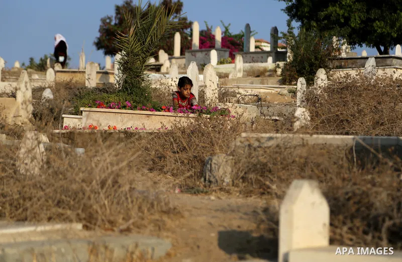 A Palestinian girl Lays flowers on the grave of her relative at a cemetery on the first day of Eid al-Adha, or feast of the sacrifice, in Gaza city, on September 1, 2017. Muslims around the world are celebrating Eid al-A...