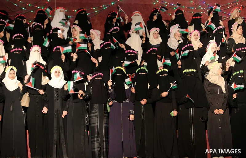 Palestinian brides waves the national flags during a mass wedding for Palestinian couples organized by Hamas movement, in Rafah in the southern Gaza Strip September 8, 2017. Photo by Ramadan El-agha