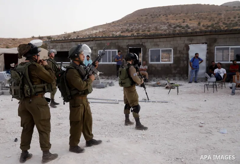 Israeli security forces stand guard as Palestinian construction laborers rebuilt a school after Israeli troops confiscated caravans used as school classrooms on August due to the lack of an Israeli-issued construction pe...