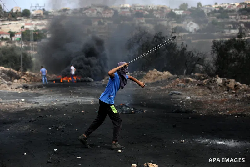 A Palestinian protester uses a slingshot to hurl stones towards Israeli security forces during clashes following demonstration against the expropriation of Palestinian land by Israel in the village of Kfar Qaddum, near N...