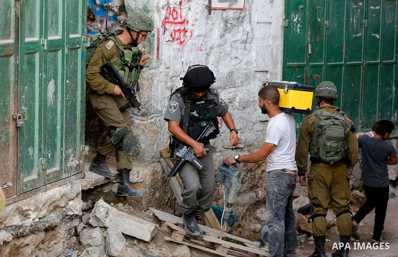 Israeli soldiers stand guard as Jewish settlers tour of the streets in the Old City of the West Bank city of Hebron on September 16, 2017. Photo by Wisam Hashlamoun
