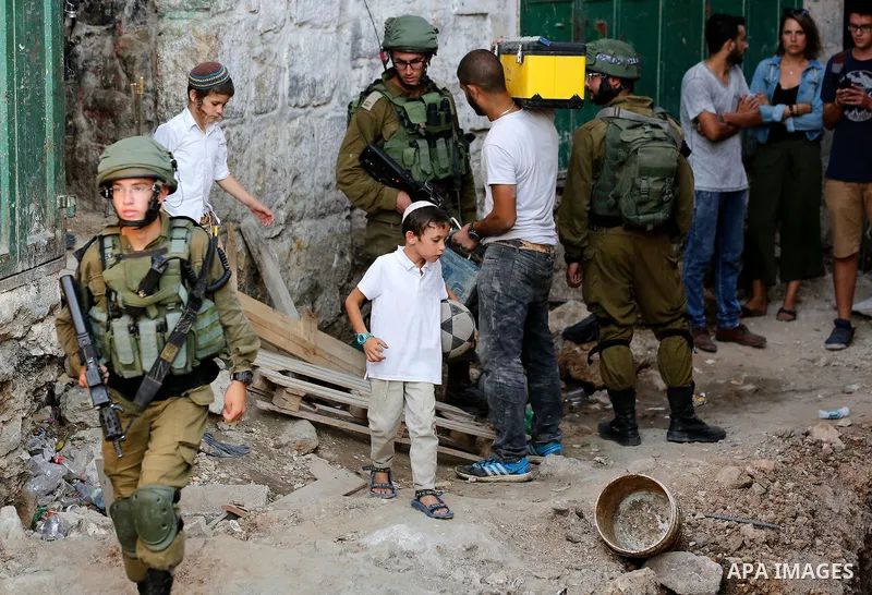 Israeli soldiers stand guard as Jewish settlers tour of the streets in the Old City of the West Bank city of Hebron on September 16, 2017. Photo by Wisam Hashlamoun