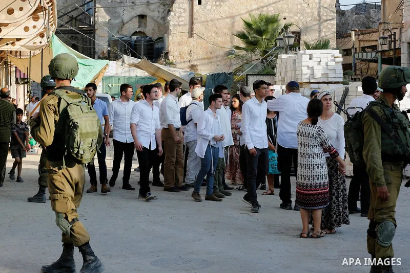 Israeli soldiers stand guard as Jewish settlers tour of the streets in the Old City of the West Bank city of Hebron on September 16, 2017. Photo by Wisam Hashlamoun