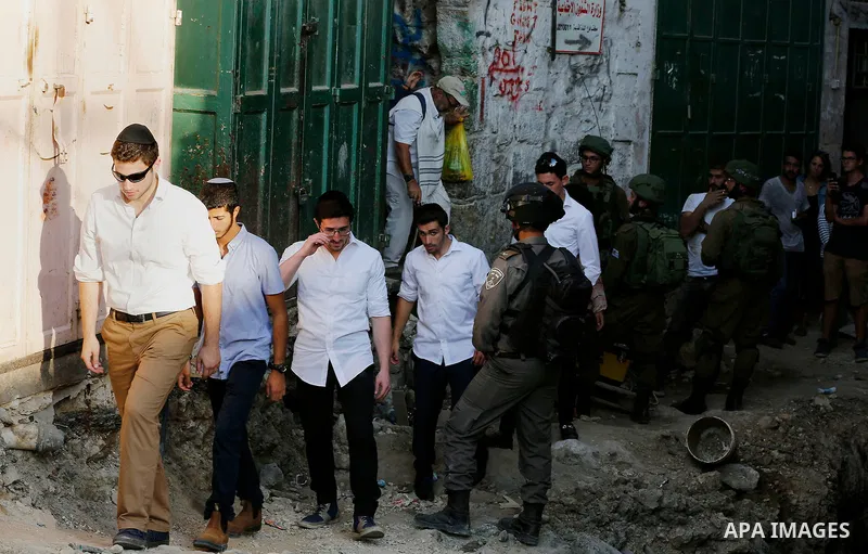 Israeli soldiers stand guard as Jewish settlers tour of the streets in the Old City of the West Bank city of Hebron on September 16, 2017. Photo by Wisam Hashlamoun