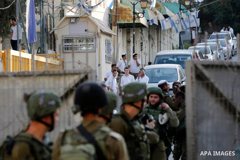 Israeli soldiers stand guard as Jewish settlers tour of the streets in the Old City of the West Bank city of Hebron on September 16, 2017. Photo by Wisam Hashlamoun