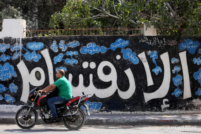 A Palestinian man rides his motorcycle past a graffiti reading in Arabic ''Division'' in Gaza City, on September 17, 2017, after Hamas announced it had agreed to steps toward resolving a decade-long split with the Fatah...