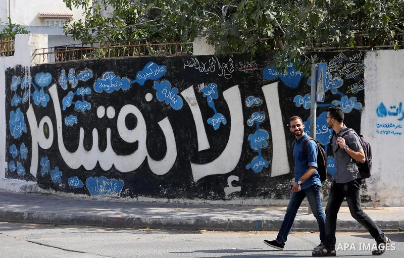 Palestinians walk past a graffiti reading in Arabic ''Division'' in Gaza City, on September 17, 2017, after Hamas announced it had agreed to steps toward resolving a decade-long split with the Fatah movement and was read...