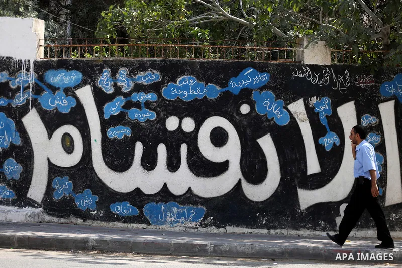 A Palestinian man walks past a graffiti reading in Arabic ''Division'' in Gaza City, on September 17, 2017, after Hamas announced it had agreed to steps toward resolving a decade-long split with the Fatah movement and wa...