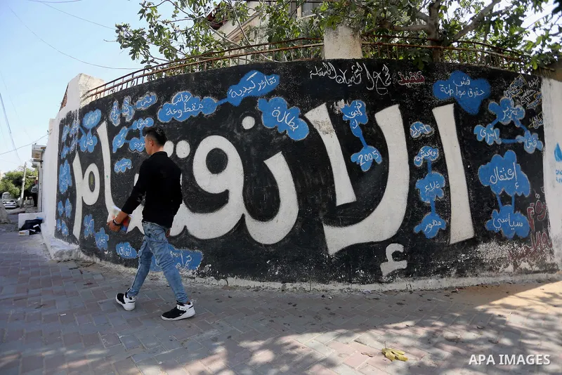 A Palestinian man walks past a graffiti reading in Arabic ''Division'' in Gaza City, on September 17, 2017, after Hamas announced it had agreed to steps toward resolving a decade-long split with the Fatah movement and wa...