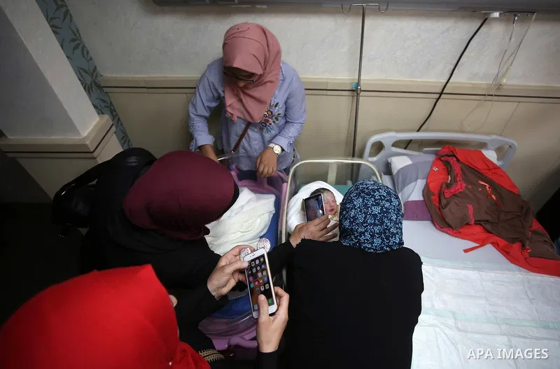Relatives gather around the twins of Palestinian prisoner Qasim al-Akeleek, 34, who were conceived with sperm from him smuggled out of an Israeli prison at Arab Specialist Hospital in the West Bank city of Nablus on Sept...