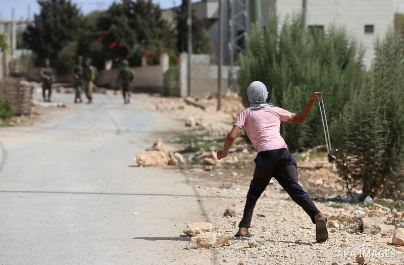A Palestinian protester throws a stone towards Israeli security forces during clashes following a demonstration against the expropriation of Palestinian land by Israel in the village of Kfar Qaddum, near Nablus in the oc...
