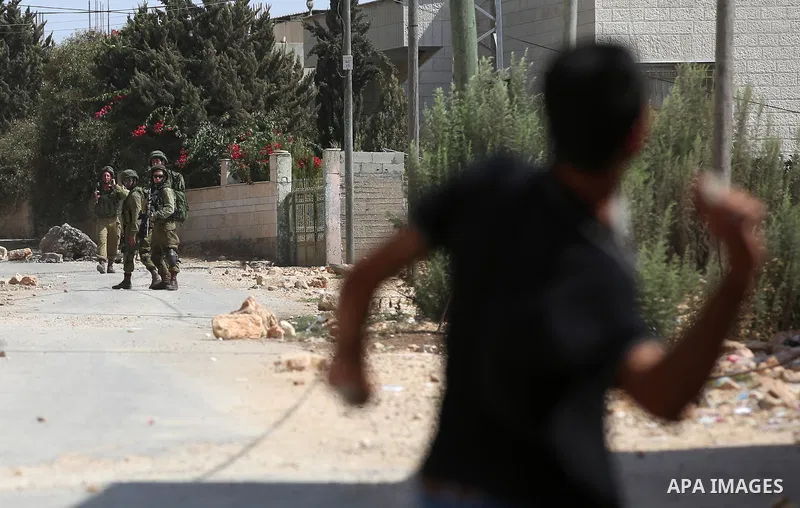 A Palestinian protester throws a stone towards Israeli security forces during clashes following a demonstration against the expropriation of Palestinian land by Israel in the village of Kfar Qaddum, near Nablus in the oc...