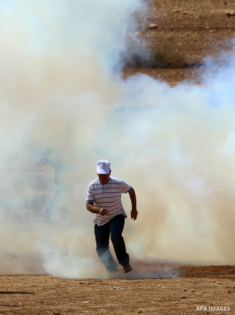 A Palestinian protester runs from a tear gas fired by Israeli security forces during clashes following a protest against the expropriation of Palestinian land in the village of Atouf, near the west bank city of Tubas on...