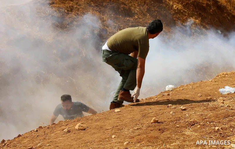 Palestinian protesters take cover from tear gas fired by Israeli security forces during clashes following a protest against the expropriation of Palestinian land in the village of Atouf, near the west bank city of Tubas...