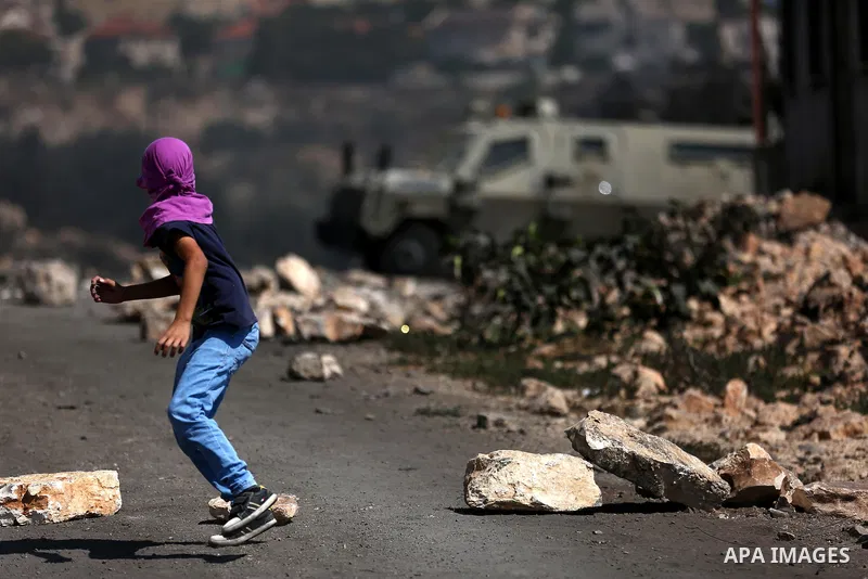 A Palestinian protester hurls stones towards Israeli troops during clashes near the Jewish settlement of Qadomem, in the West Bank village of Kofr Qadom near Nablus September 29, 2017. Photo by Ayman Ameen