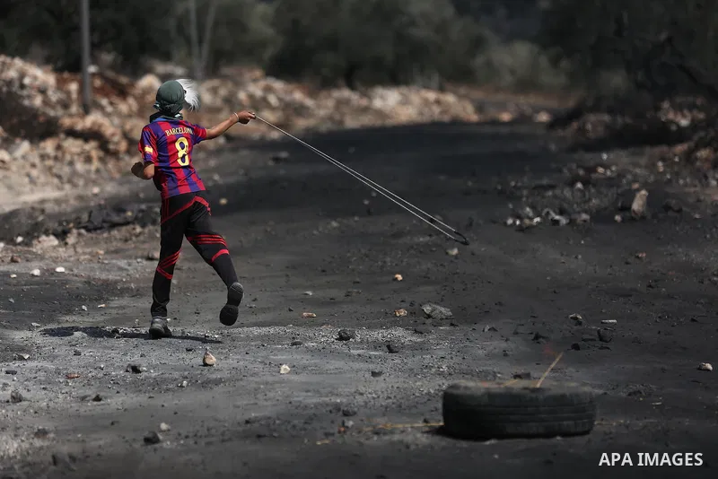 A Palestinian protester hurls stones towards Israeli troops during clashes near the Jewish settlement of Qadomem, in the West Bank village of Kofr Qadom near Nablus September 29, 2017. Photo by Ayman Ameen